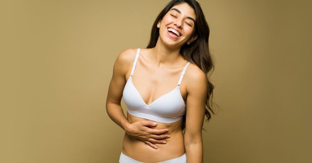 Laughing woman in white lingerie with her hand on her stomach (model)